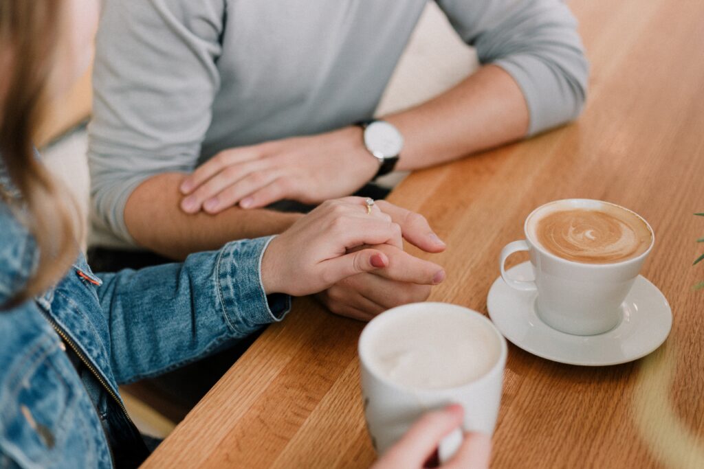 Cropped photo of couple holding hands drinking coffee arguing healthfully