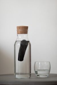 Bottle of water with charcoal filter inside beside glass of water